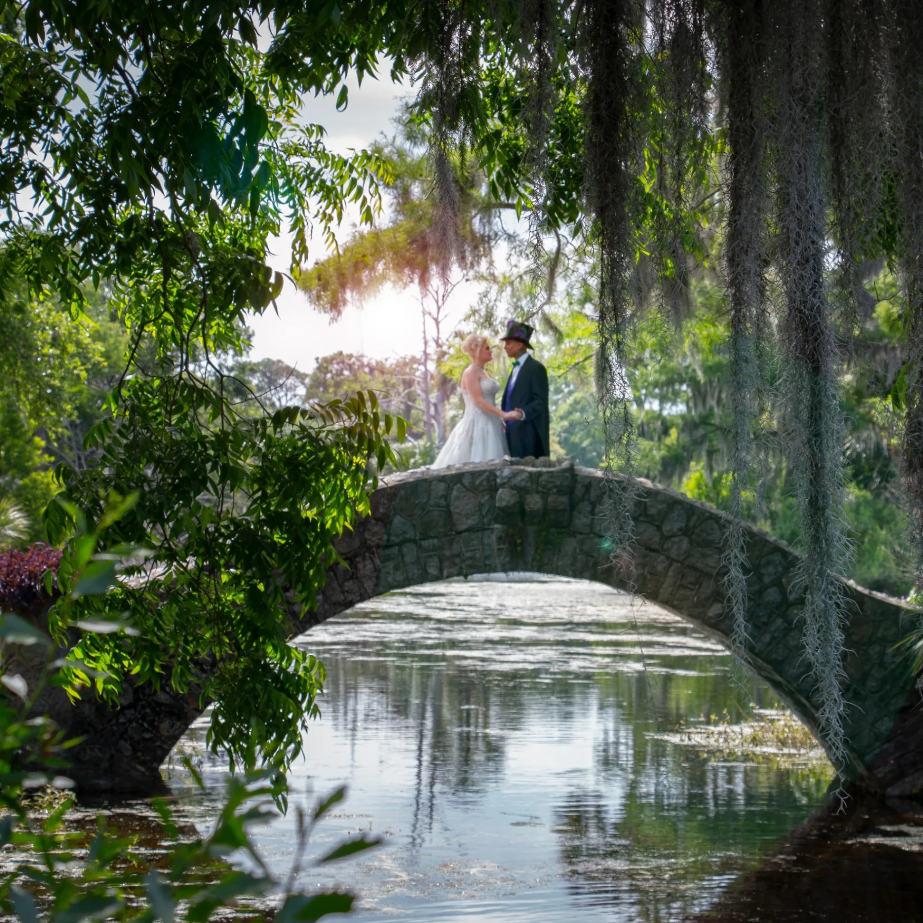 Bride and groom on a stone bridge over a City Park lagoon, framed by Spanish moss — a New Orleans wedding ceremony by Reverend Samantha McGovern.